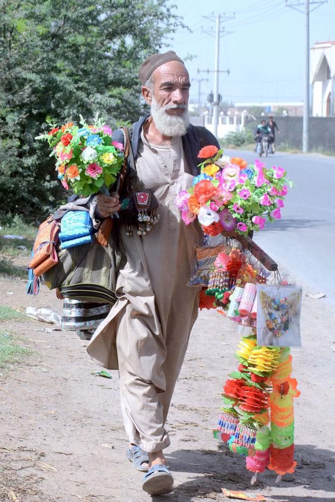 An elderly vendor displaying decorative stuff for sale to attract customers while shuttling on the road