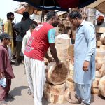 People purchasing wooden pieces to be used for chopping meat of sacrificial animals on the eve of Eid-ul-Azha