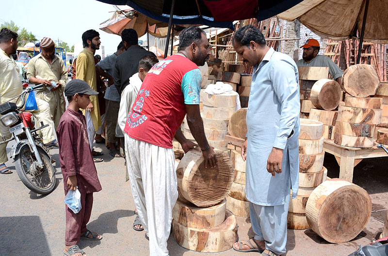 People purchasing wooden pieces to be used for chopping meat of sacrificial animals on the eve of Eid-ul-Azha