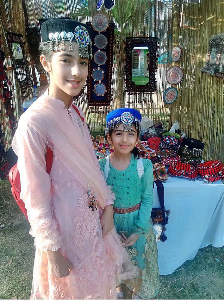 Young girls wearing traditional Kashmiri caps and posing for photograph during Saqafati Mela promoting Pakistani culture providing entertainment to public at Lok Virsa