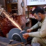 A blacksmith is sharpening knives and axes at his work-place to sell them to the butchers for using them to slaughter sacrificial animals during Eid-ul-Azha.