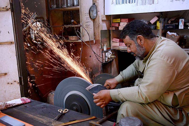 A blacksmith is sharpening knives and axes at his work-place to sell them to the butchers for using them to slaughter sacrificial animals during Eid-ul-Azha.
