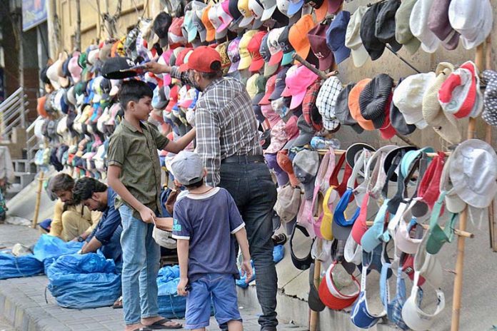 A vendor selling caps at his roadside setup in Provincial Capital A vendor selling caps at his roadside setup in Provincial Capital