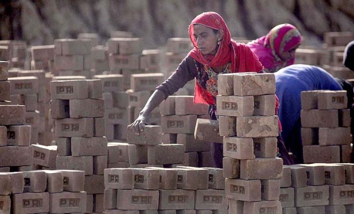 A labourer arranging raw bricks at a local brick kiln