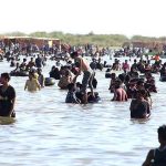 A large number of people enjoy bathing at keenjhar Lake during hot day in the city