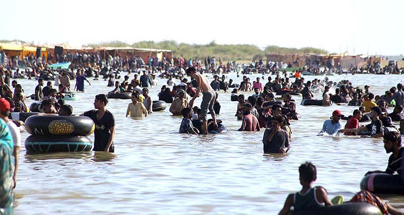 A large number of people enjoy bathing at keenjhar Lake during hot day in the city