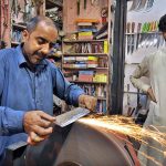 A blacksmith busy in sharpening knives to be used for slaughtering sacrificial animals on th eoccasion of Eidul Azha
