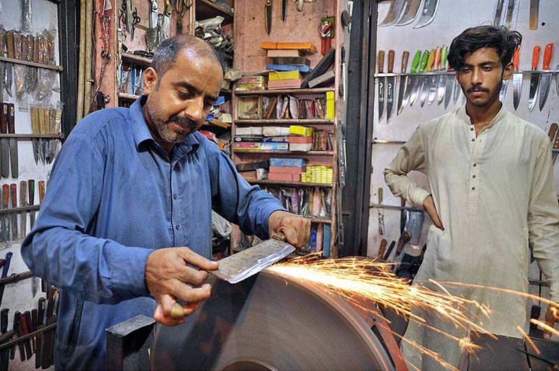 A blacksmith busy in sharpening knives to be used for slaughtering sacrificial animals on th eoccasion of Eidul Azha