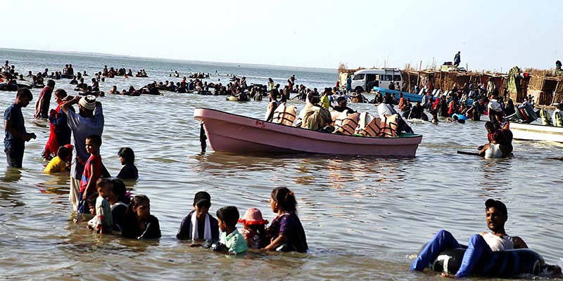 A large number of people enjoy bathing at keenjhar Lake during hot day in the city