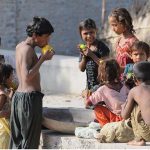 Gypsy children enjoy eating seasonal fruit mangoe outside of their makeshift home