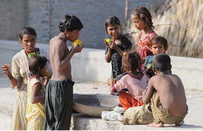 Gypsy children enjoy eating seasonal fruit mangoe outside of their makeshift home
