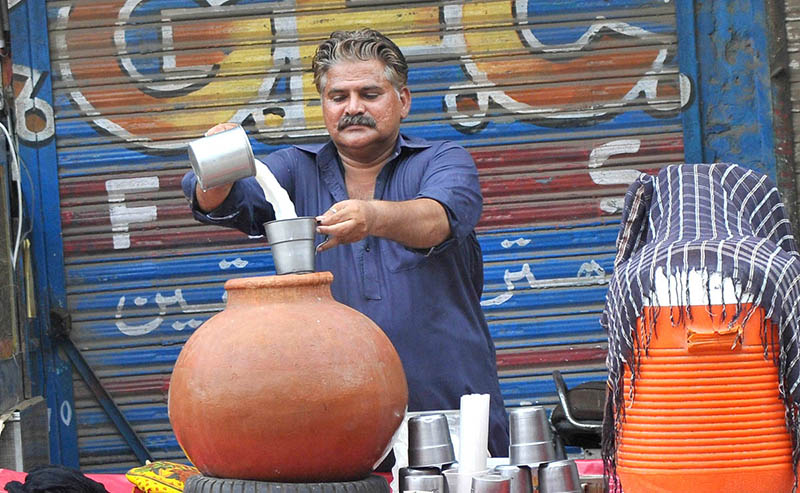 A vendor selling a traditional summer drink (Lassi) at his roadside setup