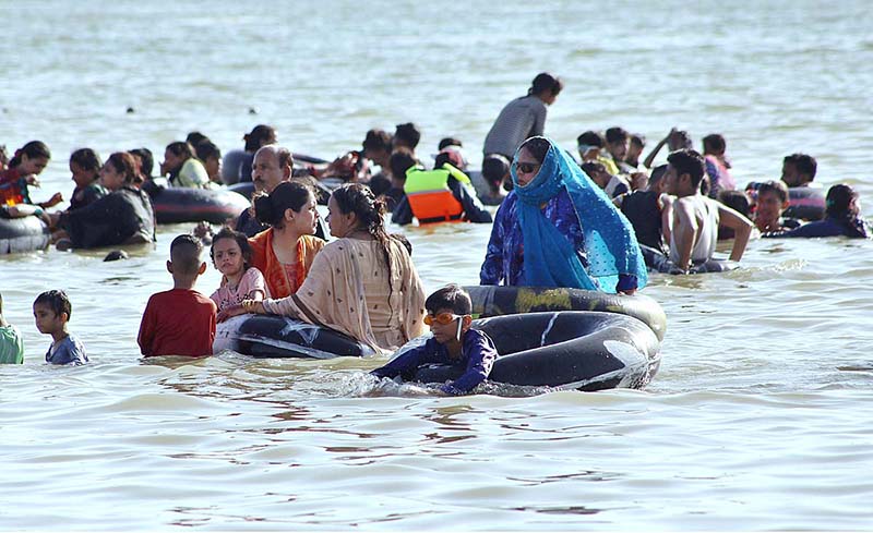 A large number of people enjoy bathing at keenjhar Lake during hot day in the city