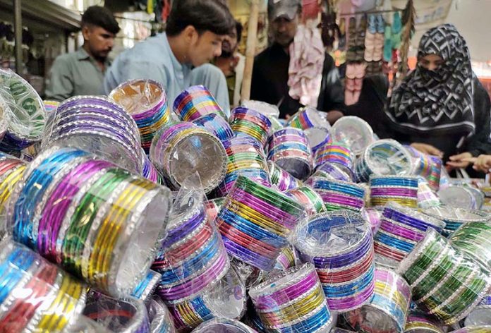 A vendor displaying colourful bangles to attract the customers at Resham Gali in connection with upcoming Eidul Azha