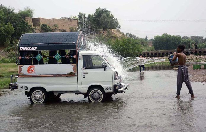 A person washing his vehicle in a local stream at Dando Pull area near Phandu