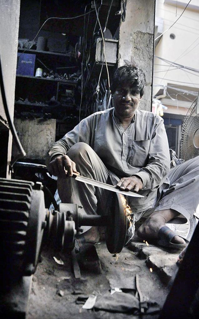 A blacksmith busy in sharpen knives to be used for slaughtering sacrificial animals during Eidul Azha