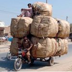 Motorcycle loader taking away empty bottles to packing point from where they would be taken to recycling factory