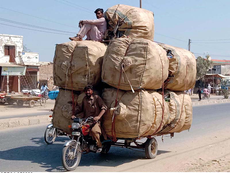 Motorcycle loader taking away empty bottles to packing point from where they would be taken to recycling factory