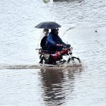 A motorcyclist passing through water accumulated on road during heavy rain that experienced the city