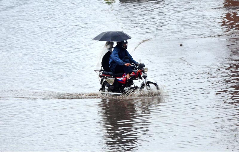 A motorcyclist passing through water accumulated on road during heavy rain that experienced the city