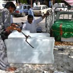 An ice seller is shoveling ice from a car in the Durogha market in the sweltering heat