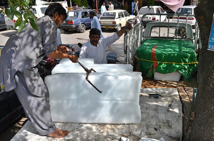 An ice seller is shoveling ice from a car in the Durogha market in the sweltering heat