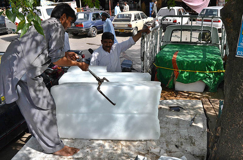 An ice seller is shoveling ice from a car in the Durogha market in the sweltering heat