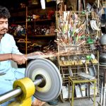 A vendor sharpening the knife to be used for slaughtering the sacrificial animals during Eid ul Azha