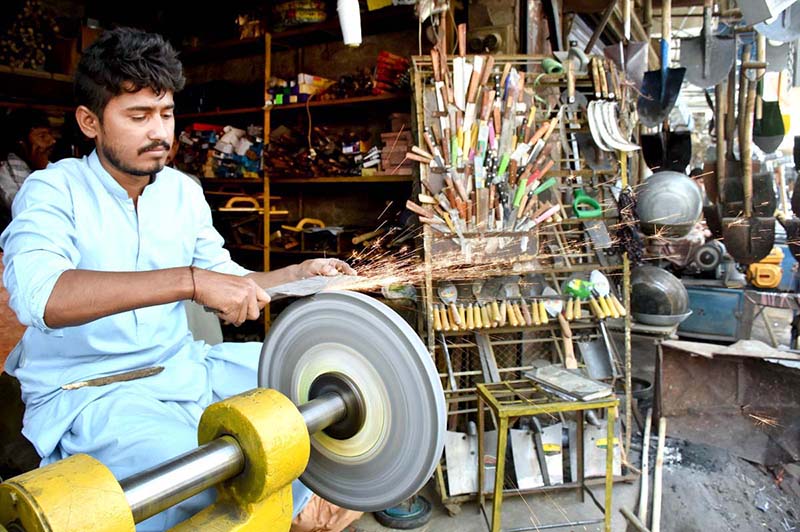 A vendor sharpening the knife to be used for slaughtering the sacrificial animals during Eid ul Azha