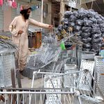A man displaying equipment of barbeques to attract customers ahead of Eid-ul Azha at Joint Road