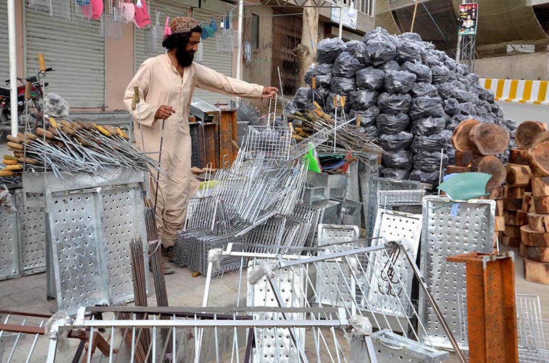 A man displaying equipment of barbeques to attract customers ahead of Eid-ul Azha at Joint Road