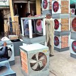 A worker is preparing room coolers at his workplace due to its increasing demand during summer season