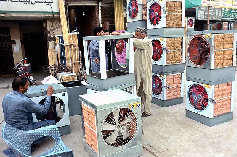 A worker is preparing room coolers at his workplace due to its increasing demand during summer season