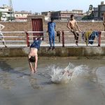 Youngsters enjoying bath in a canal to get relief from hot weather in the city