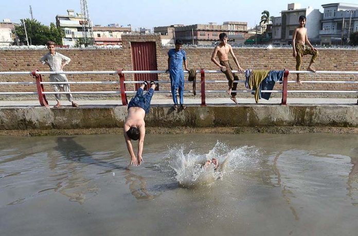 Youngsters enjoying bath in a canal to get relief from hot weather in the city