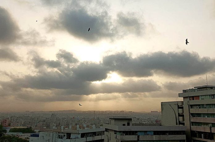 As the sun begins its descent, a breathtaking scene unfolds with its radiant glow peeking through a mesmerizing tapestry of dark clouds, painting the sky with a captivating blend of light and shadow