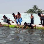 Youngsters enjoy jumping and bathing in a pond to beat the heat at the eastern bypass area of the city