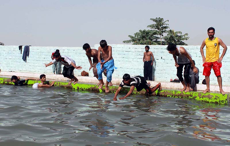 Youngsters enjoy jumping and bathing in a pond to beat the heat at the eastern bypass area of the city