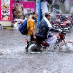 Motorcyclist passing through water accumulated on road during heavy rain that experienced the Provincial Capital