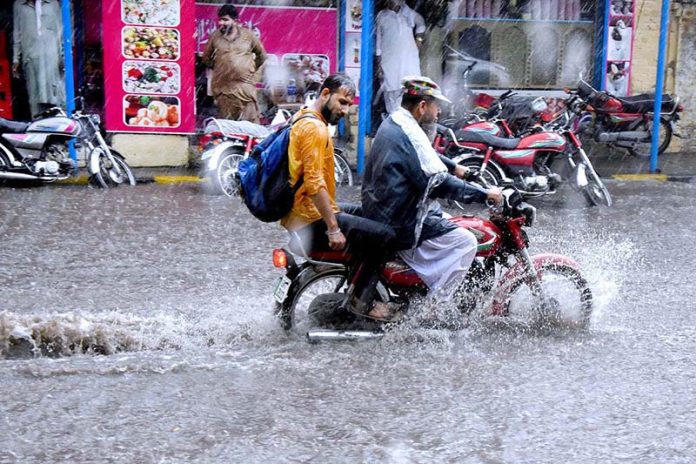 Motorcyclist passing through water accumulated on road during heavy rain that experienced the Provincial Capital