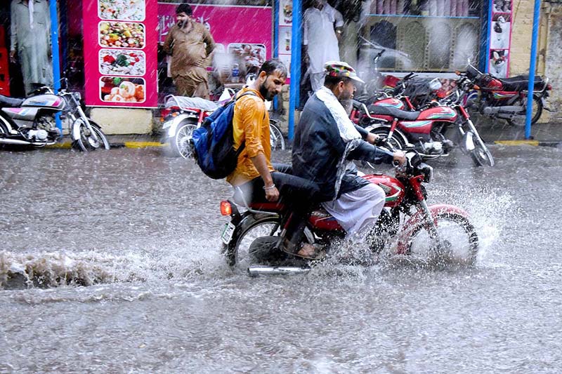 Motorcyclist passing through water accumulated on road during heavy rain that experienced the Provincial Capital