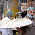 Worker carrying traditional food item ‘samosas’ in a tray for frying at his workplace