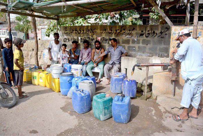People filling their pots with drinking water from hand pump due to shortage of water in the area