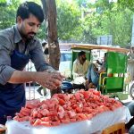 A vendor arranging and displaying watermelon pieces on handcart to attract the customers at his roadside setup