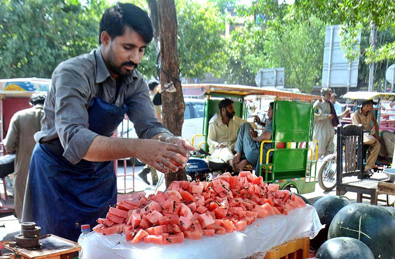 A vendor arranging and displaying watermelon pieces on handcart to attract the customers at his roadside setup