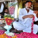 A vendor preparing garlands of fresh flowers to attract the customers at his shop