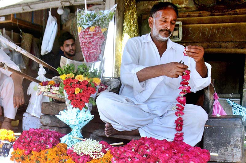 A vendor preparing garlands of fresh flowers to attract the customers at his shop