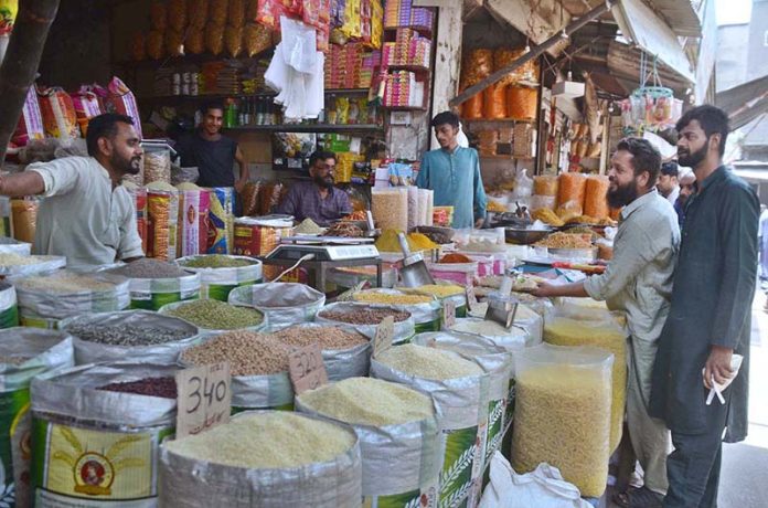 A shopkeeper waits for the customers to sell pulses at his shop in Akbari Mandi in Provincial Capital