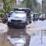 Vehicles are passing through water accumulated on road after heavy rain in the city