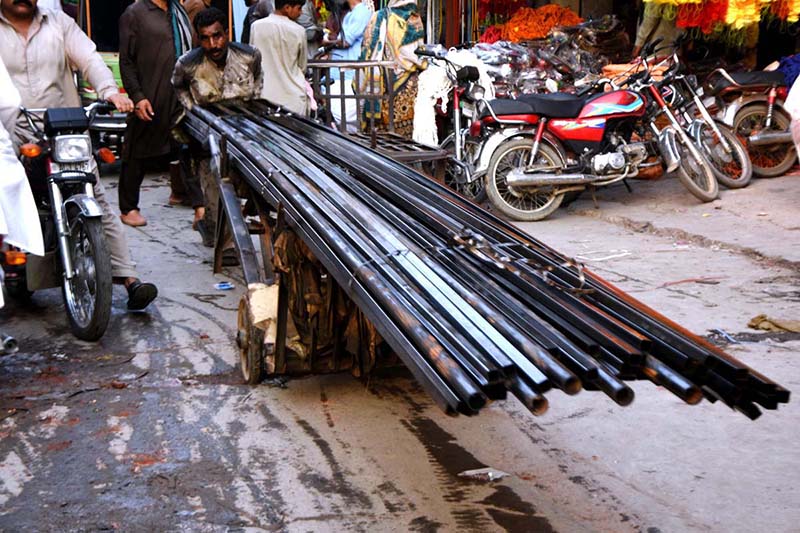 A labourer pushing handcart loaded with iron rods to deliver in a local market outside Dehli Gate in Provincial Capital